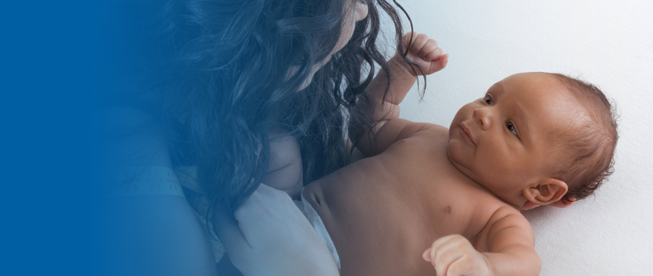 Photograph of a baby lying on its back on a blanket, making eye contact with its mother. There is a blue gradient extending to the left that becomes fainter as it progresses until it is entirely blue.