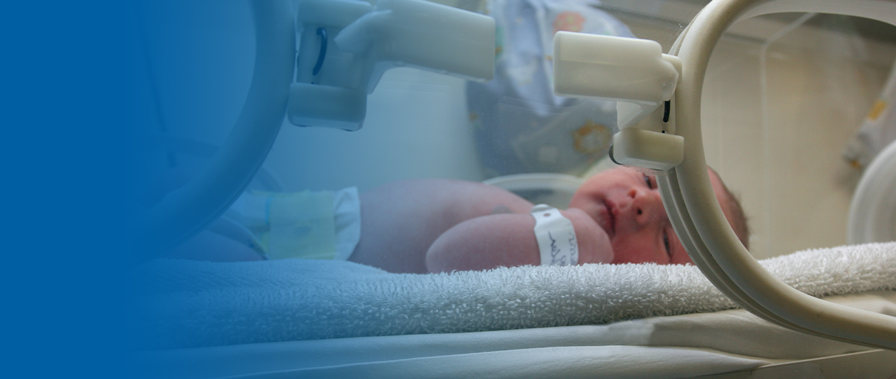 Photograph of a baby in an incubator. There is a blue gradient extending to the left that becomes fainter as it progresses until it is entirely blue.